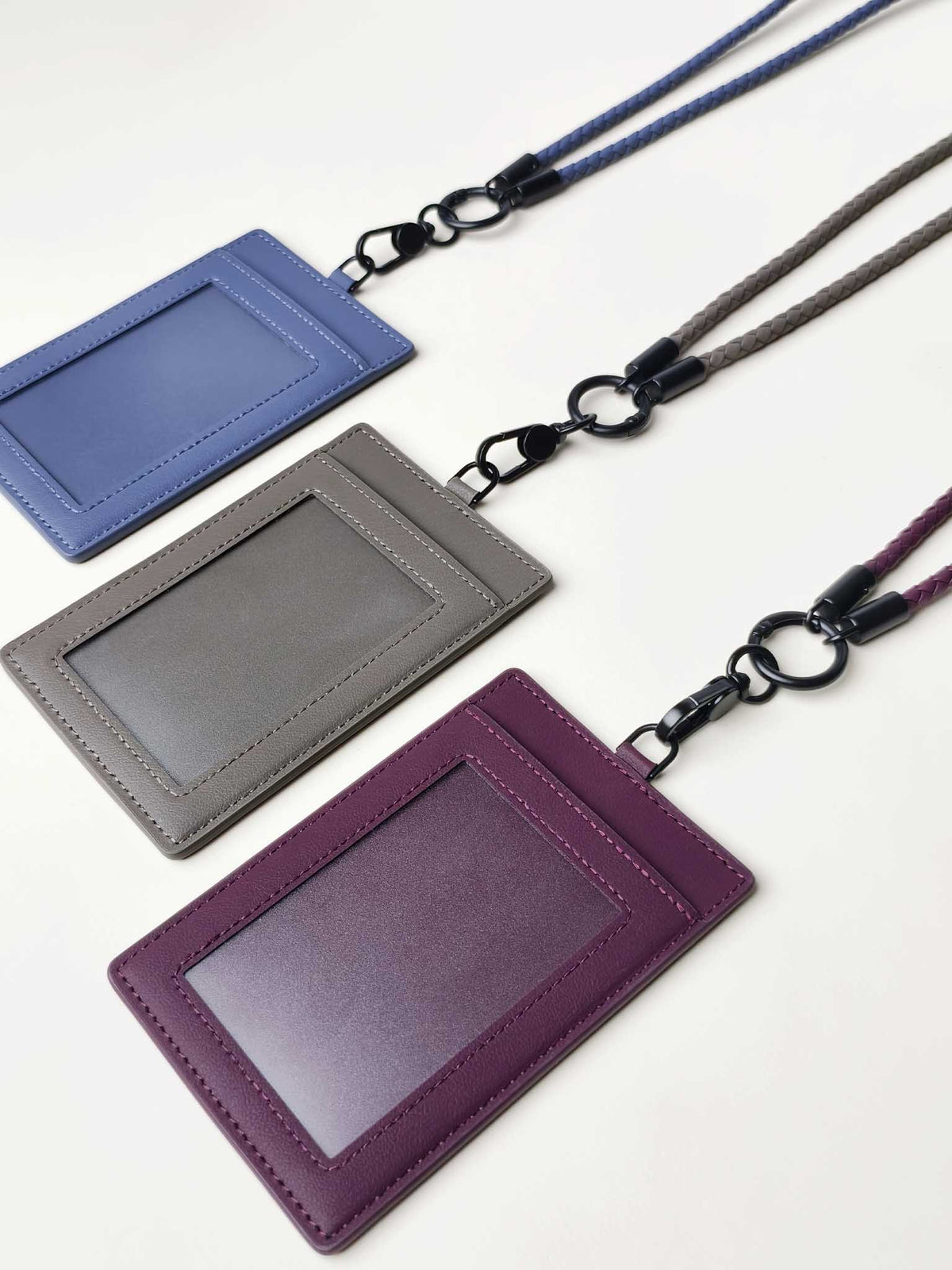 Three sicora vegan leather ID badge holders with braided lanyards, shown in blue, gray, and purple on a white background.