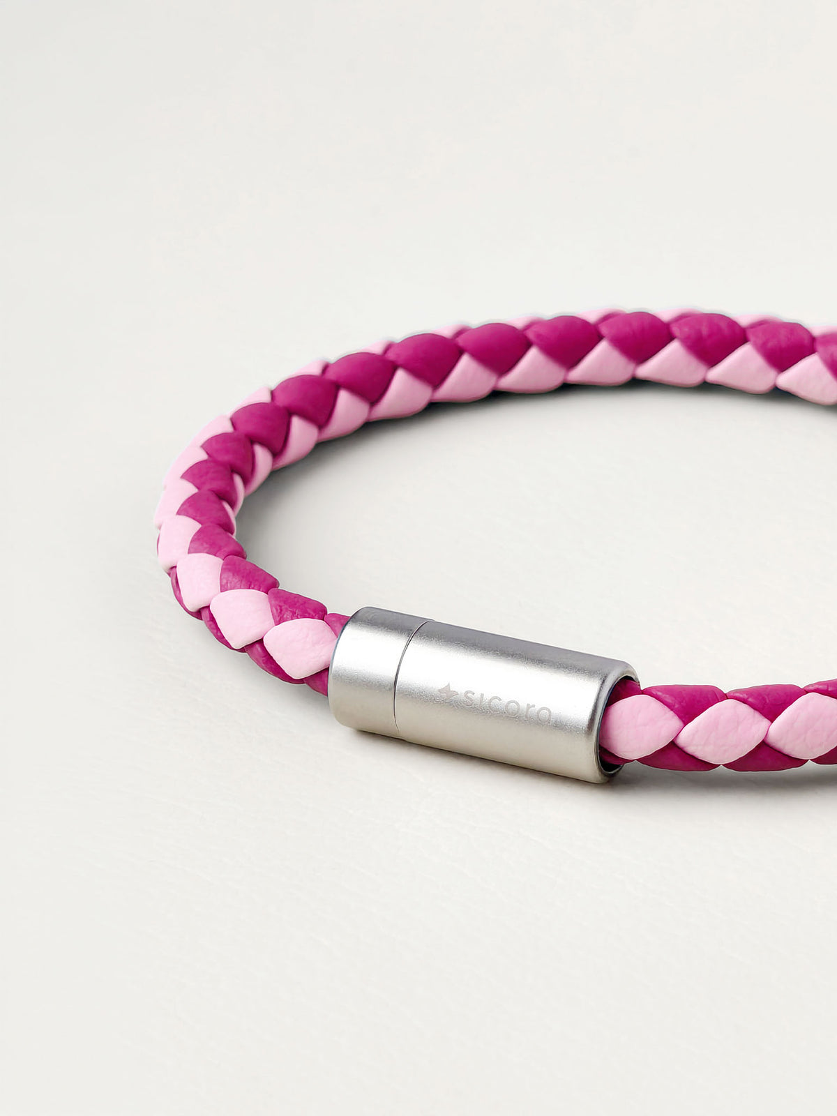 Close-up of a sicora pink and magenta duo-tone braided silio silicone vegan leather bracelet with a stainless steel metal magnetic clasp