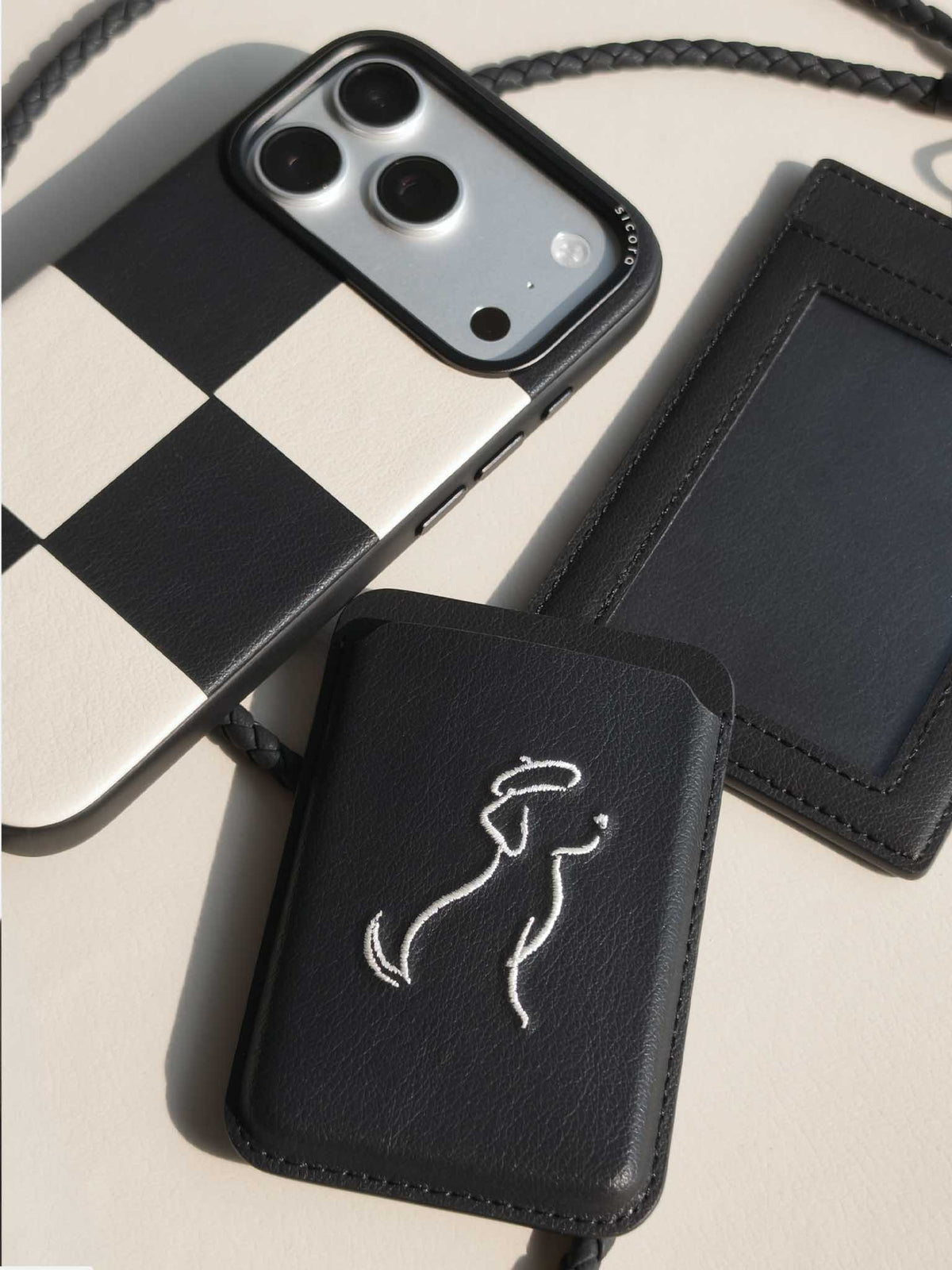 Flat-lay of sicora vegan leather products: iPhone 18 pro case, magnetic card wallet, and ID badge holder with lanyard