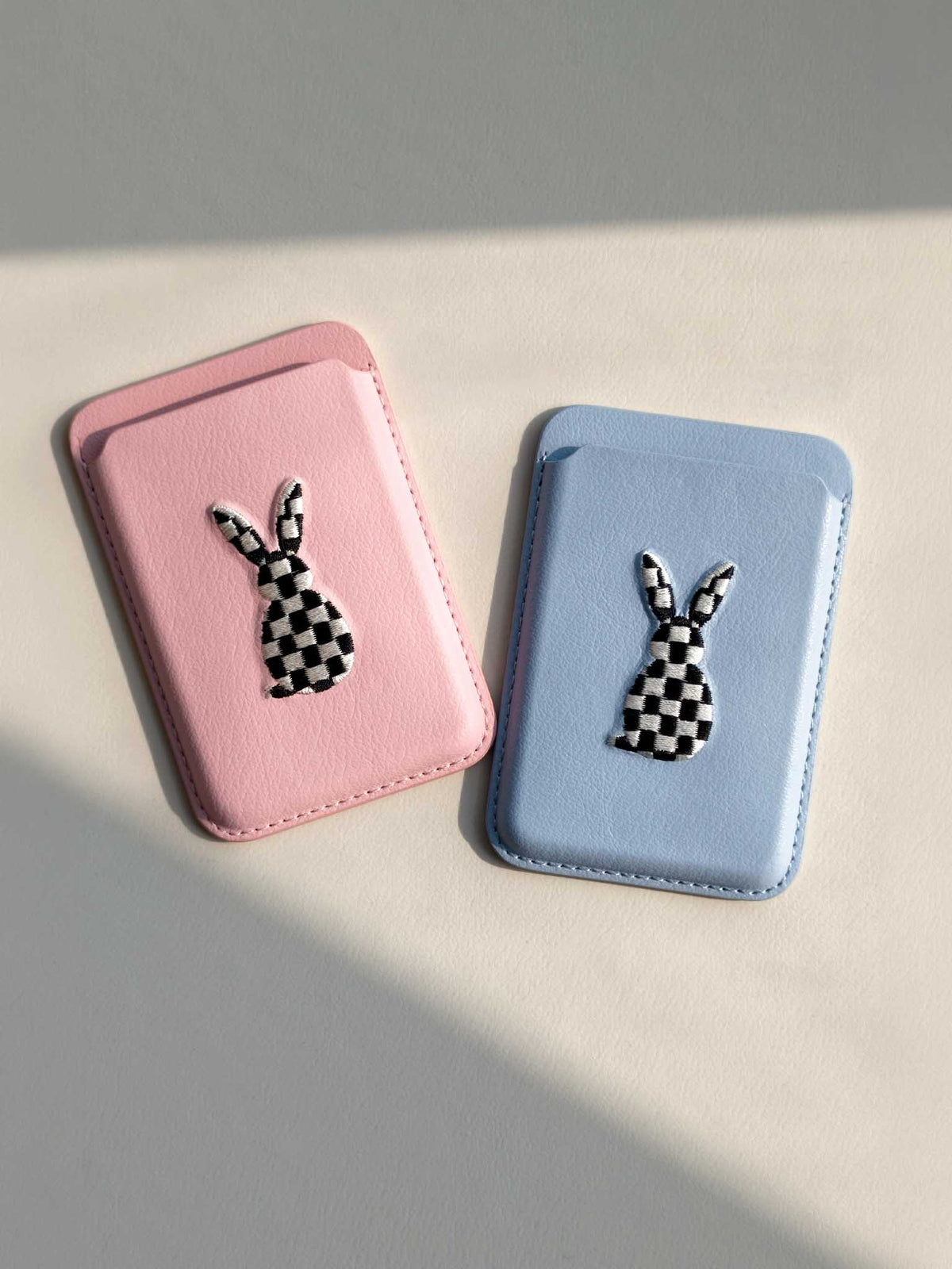 Two sicora graphic magnetic card wallets (The Dreamer Collection) in pink and light blue, each wallet has a minimalist line-art embroidery on the front.