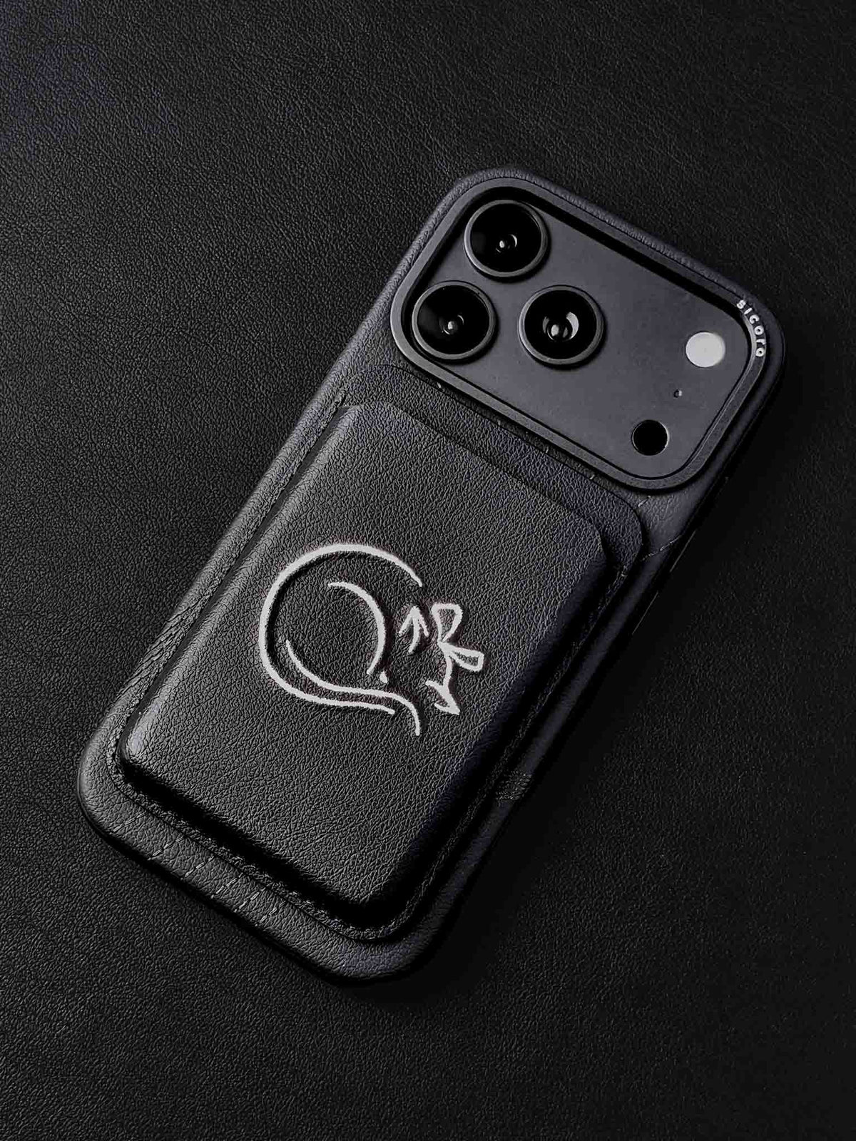 sicora vegan leather graphic magnetic card wallet in black with cream white embroidered cat line-drawing on a sicora iPhone 18 pro case
