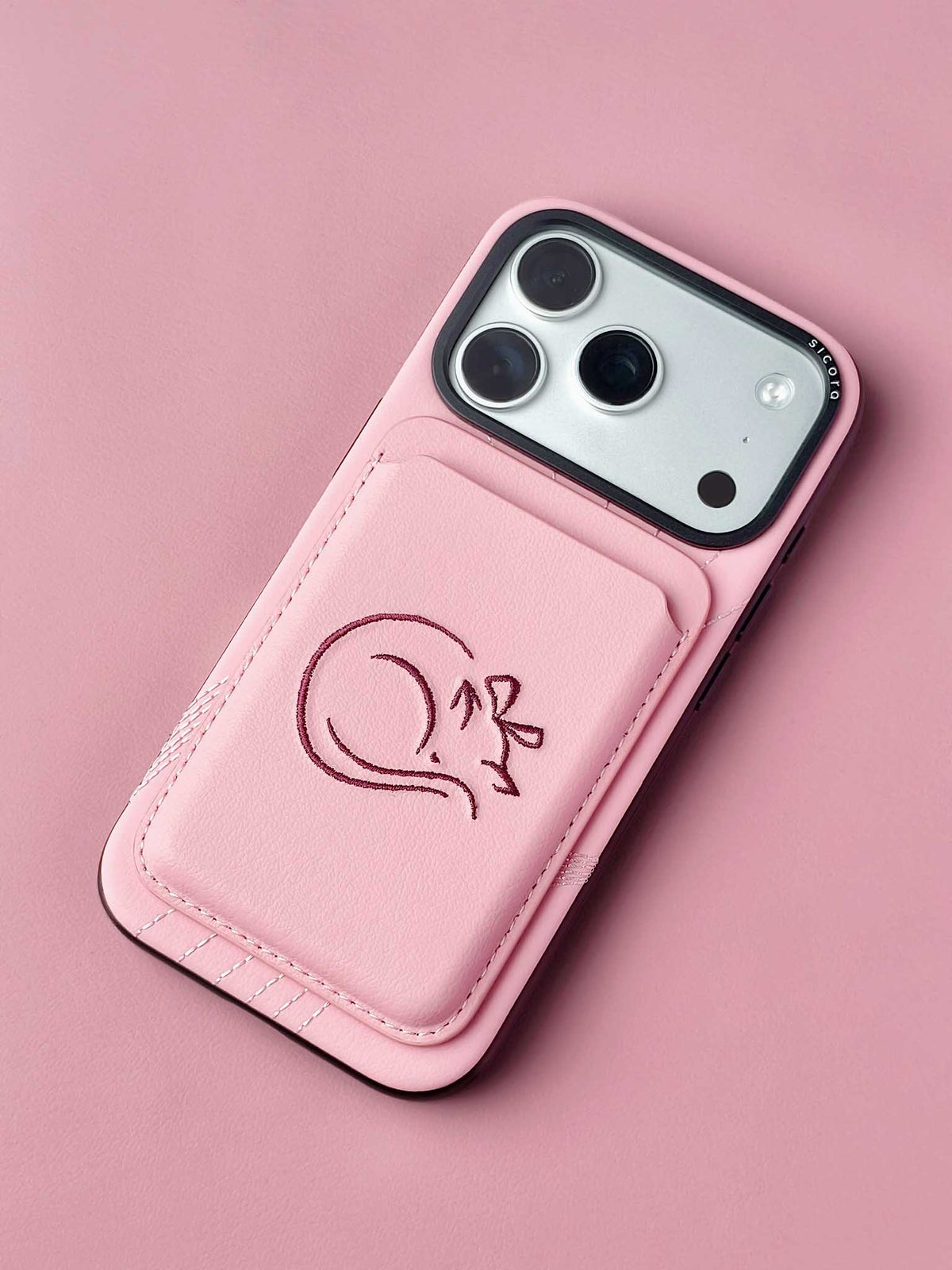 sicora vegan leather graphic magnetic card wallet in pink with dark burgundy embroidered cat line-drawing on a sicora iPhone 18 / 17 pro case