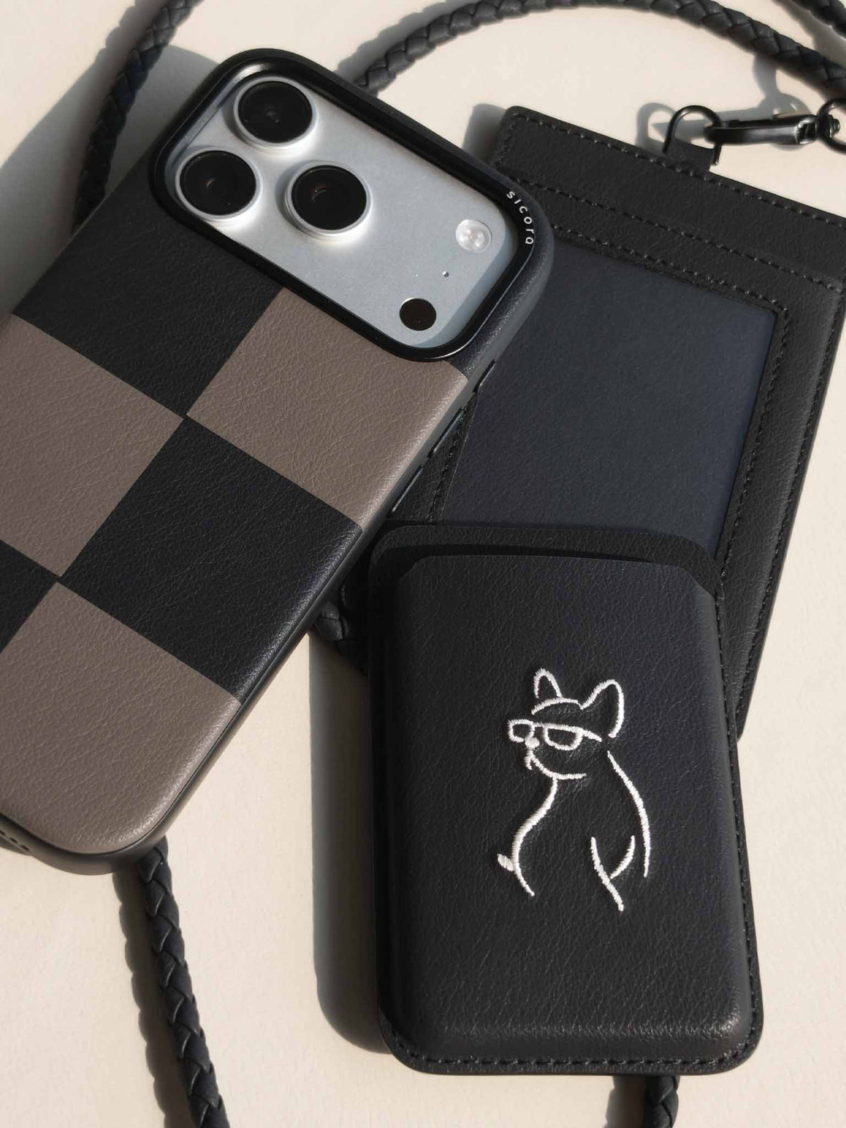 Flat-lay of sicora vegan leather products: iPhone 18 pro case, magnetic card wallet, and ID badge holder with lanyard