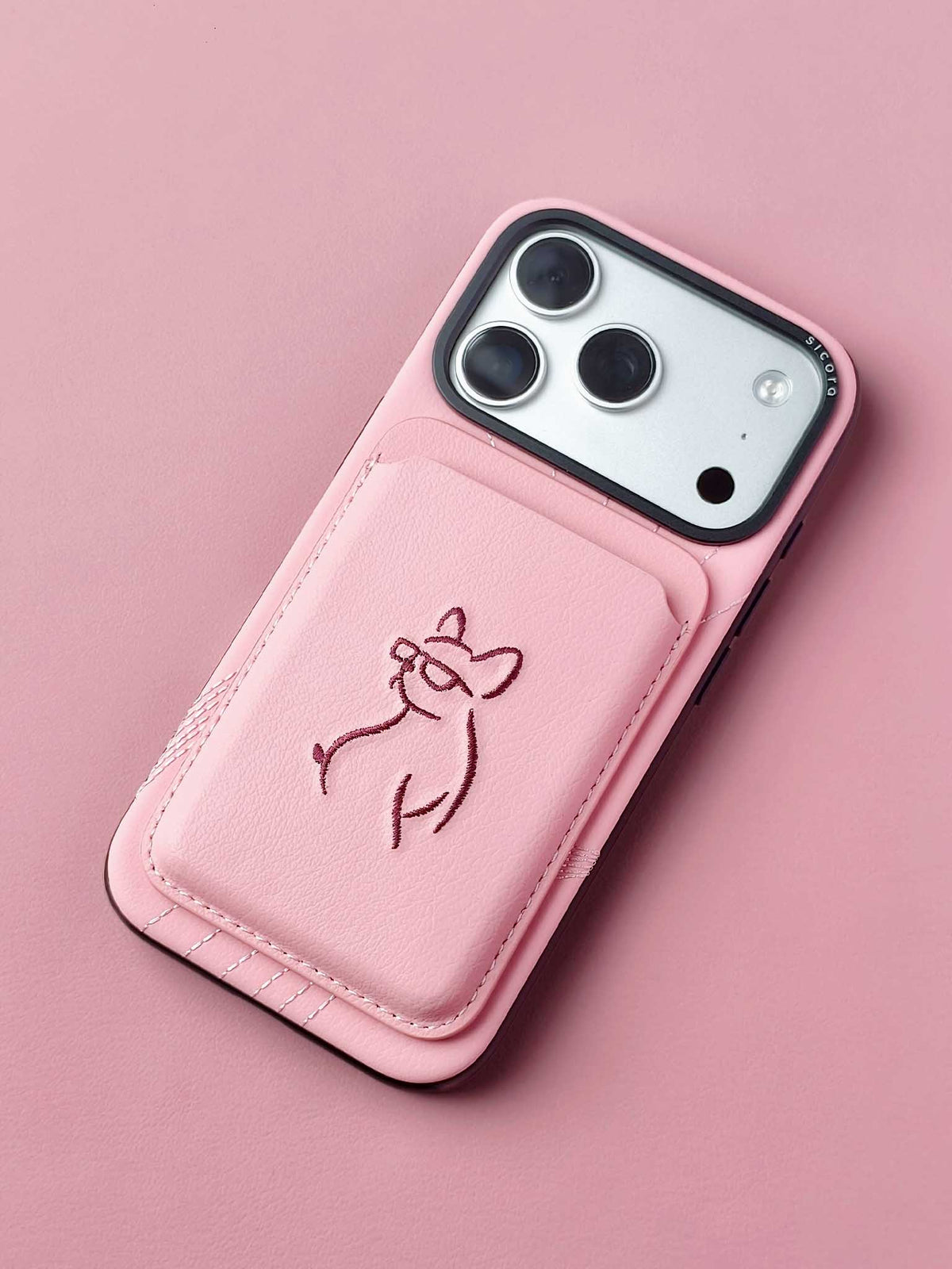 sicora vegan leather graphic magnetic card wallet in pink with dark burgundy embroidered dog line-drawing on a sicora iPhone 18 / 17 pro case