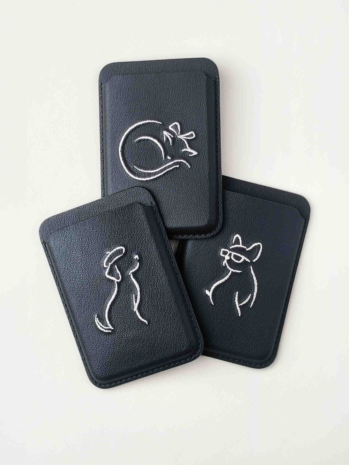 Three sicora vegan leather graphic magnetic card wallets in black with cream white embroidered minimalist animal artworks