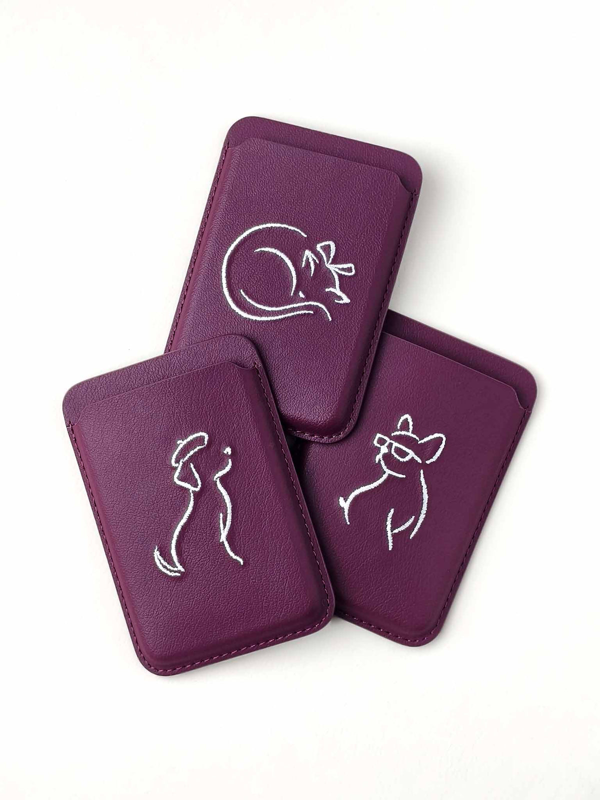Three sicora vegan leather graphic magnetic card wallets in cherry purple with cream white embroidered minimalist animal artworks