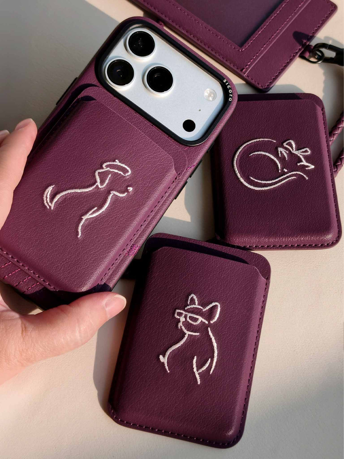 Product shot of cherry purple sicora vegan leather accessories: iPhone 18 / 17 pro case, magnetic card wallets, and ID badge holder with lanyard