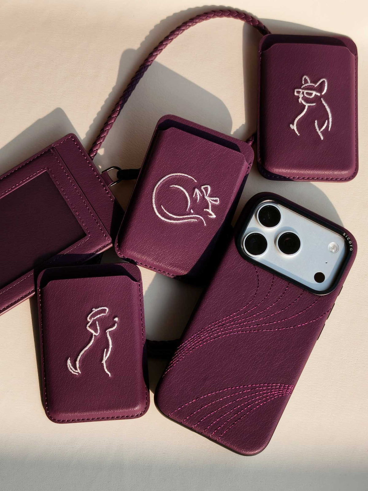 Flat-lays of cherry purple sicora vegan leather accessories: iPhone 18 / 17 pro case, magnetic card wallets, and ID badge holder with lanyard