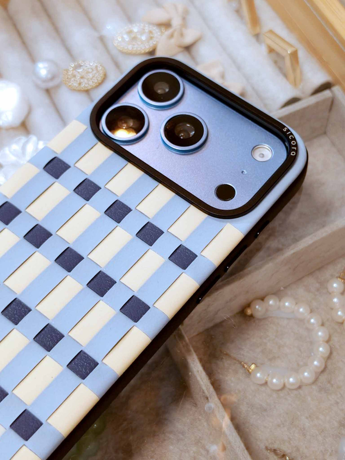 A light blue sicora iPhone 18 pro vegan leather case, pixel case laying against glass table top