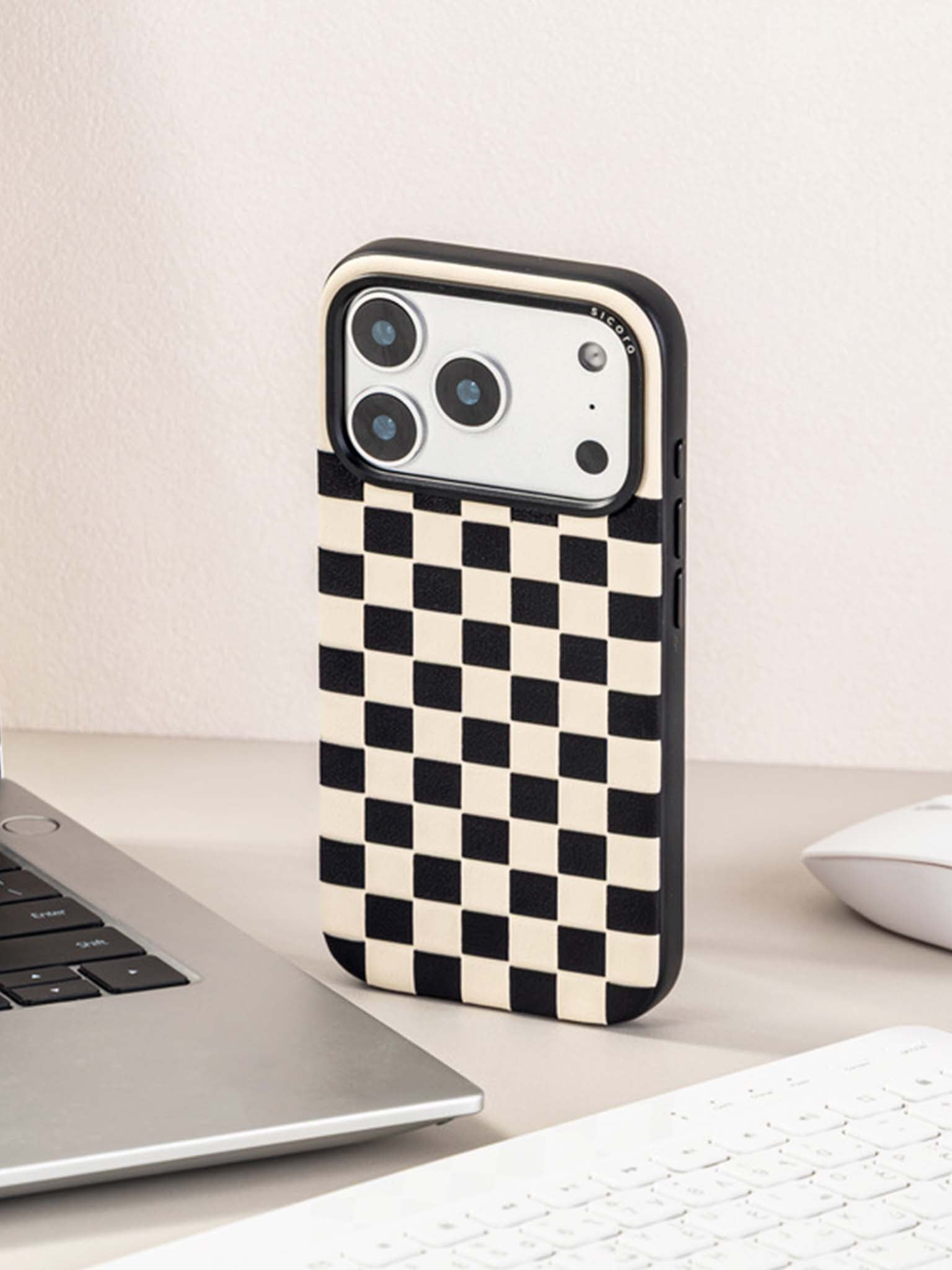 Sicora checkerboard phone case with black and cream white checkered pattern on a desk with a laptop