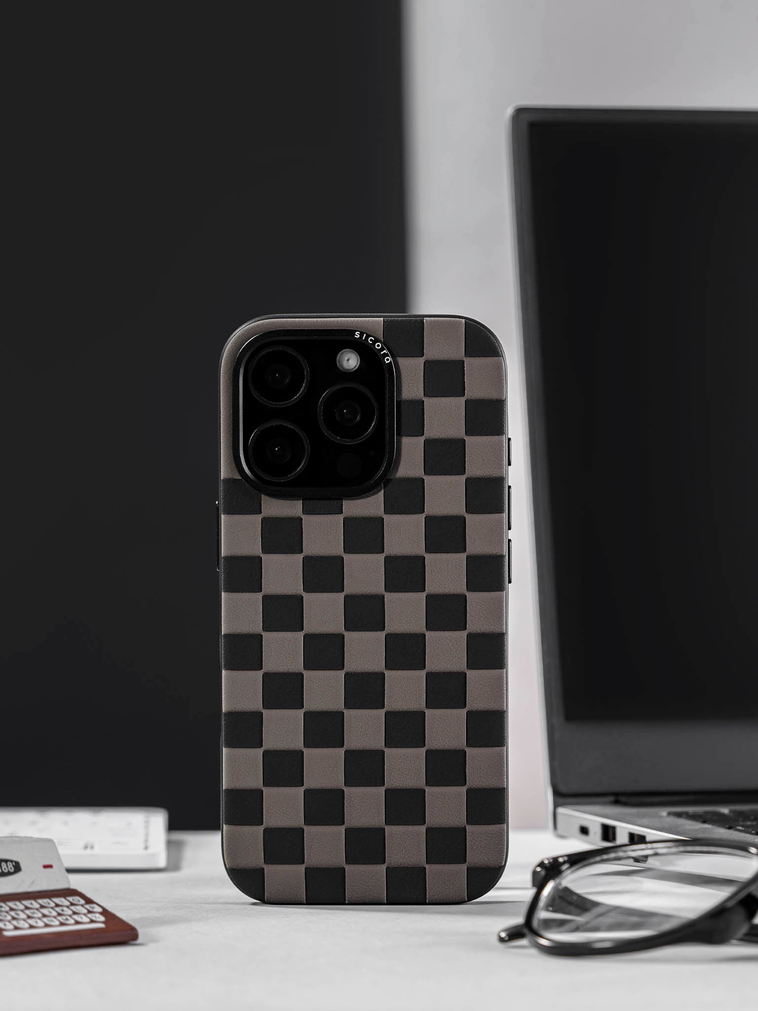 sicora black and gray checkerboard iPhone case on a desk