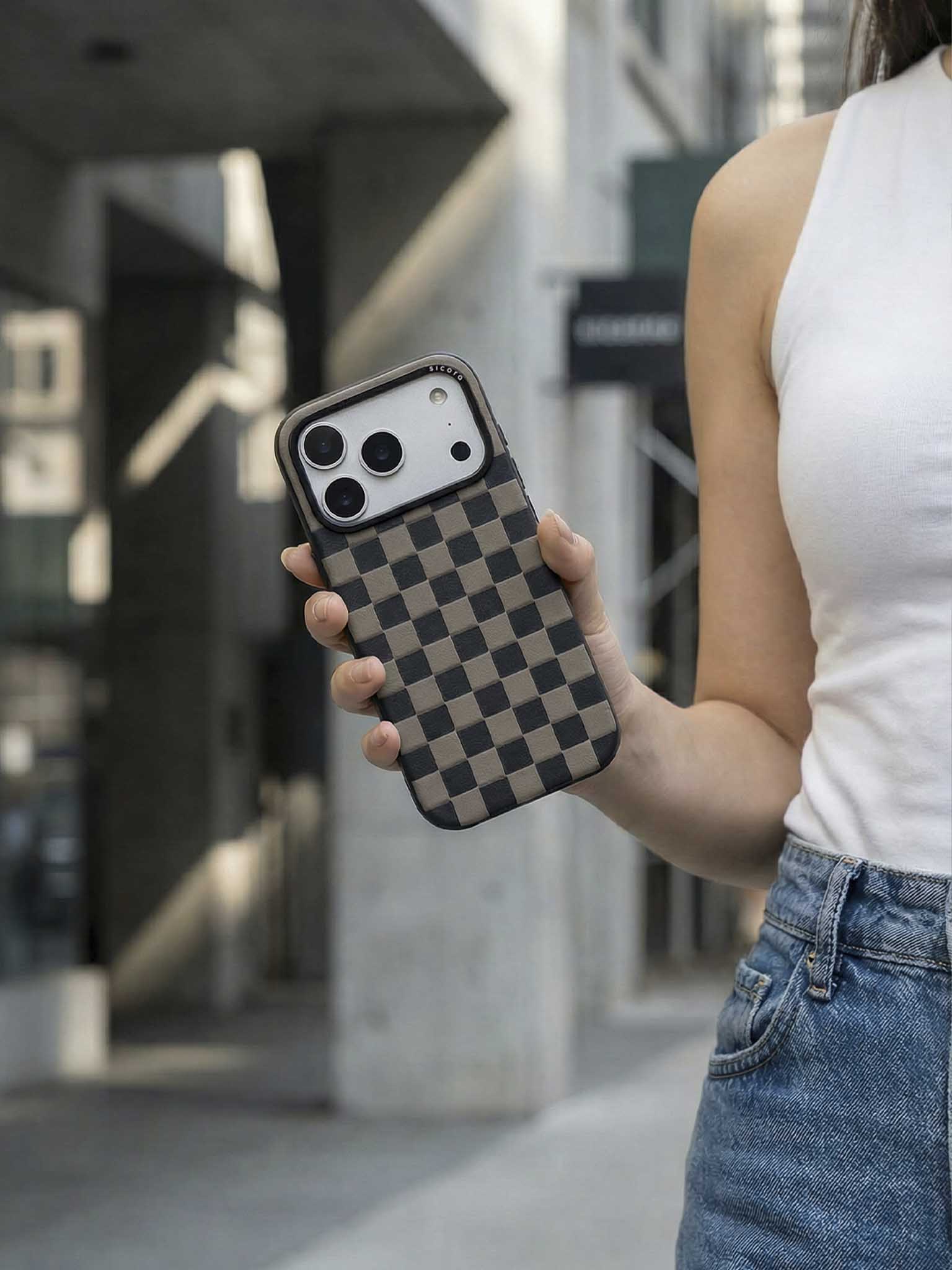 Person holding a sicora checkerboard phone case in an urban setting