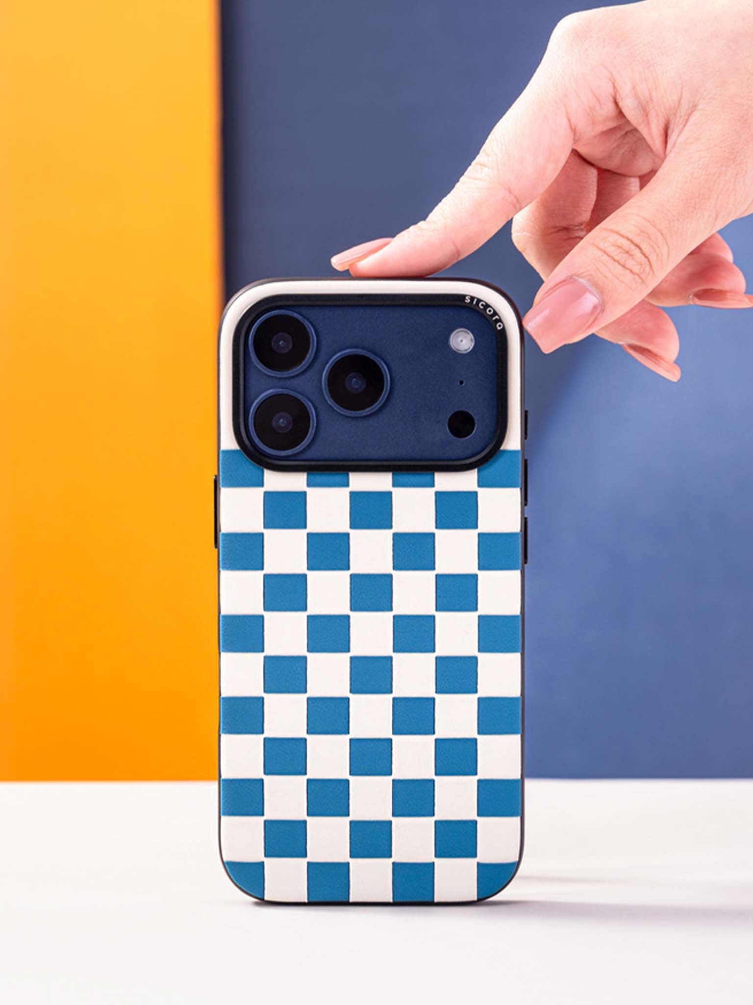 Sicora checkerboard phone case with sea blue and cream white checkered pattern held by a hand against a colorful background