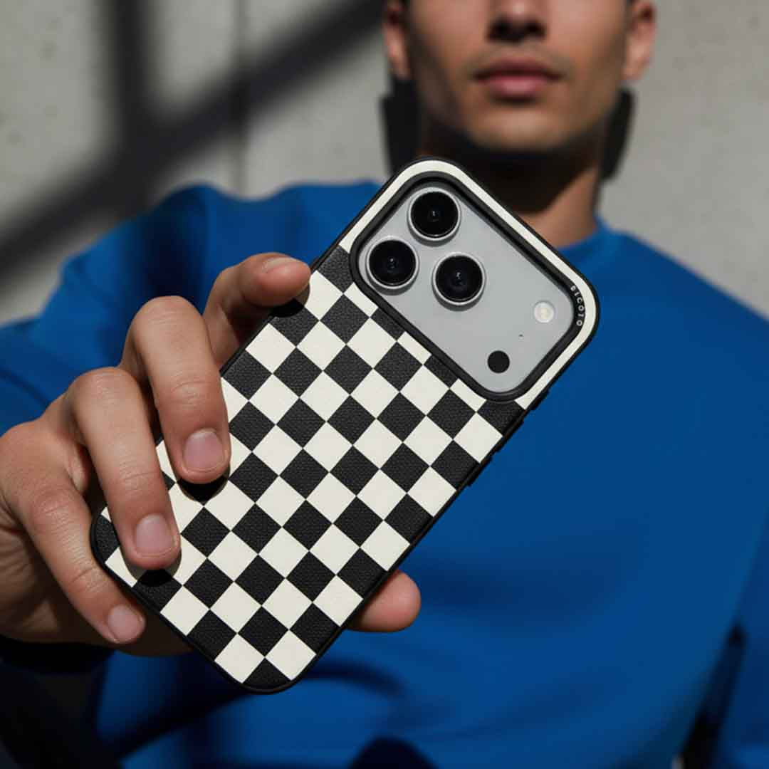A man holding a sicora checkerboard iPhone case in black and cream white checkered pattern silio silicone vegan leather 