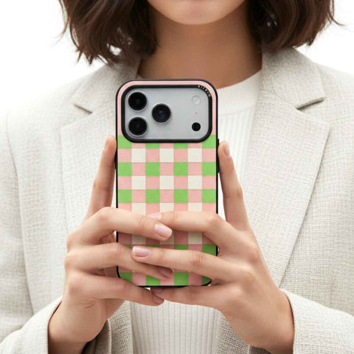 A woman holding a sicora checkerboard iPhone case in pink, avocado green and cream white checkered patterned silio silicone vegan leather 