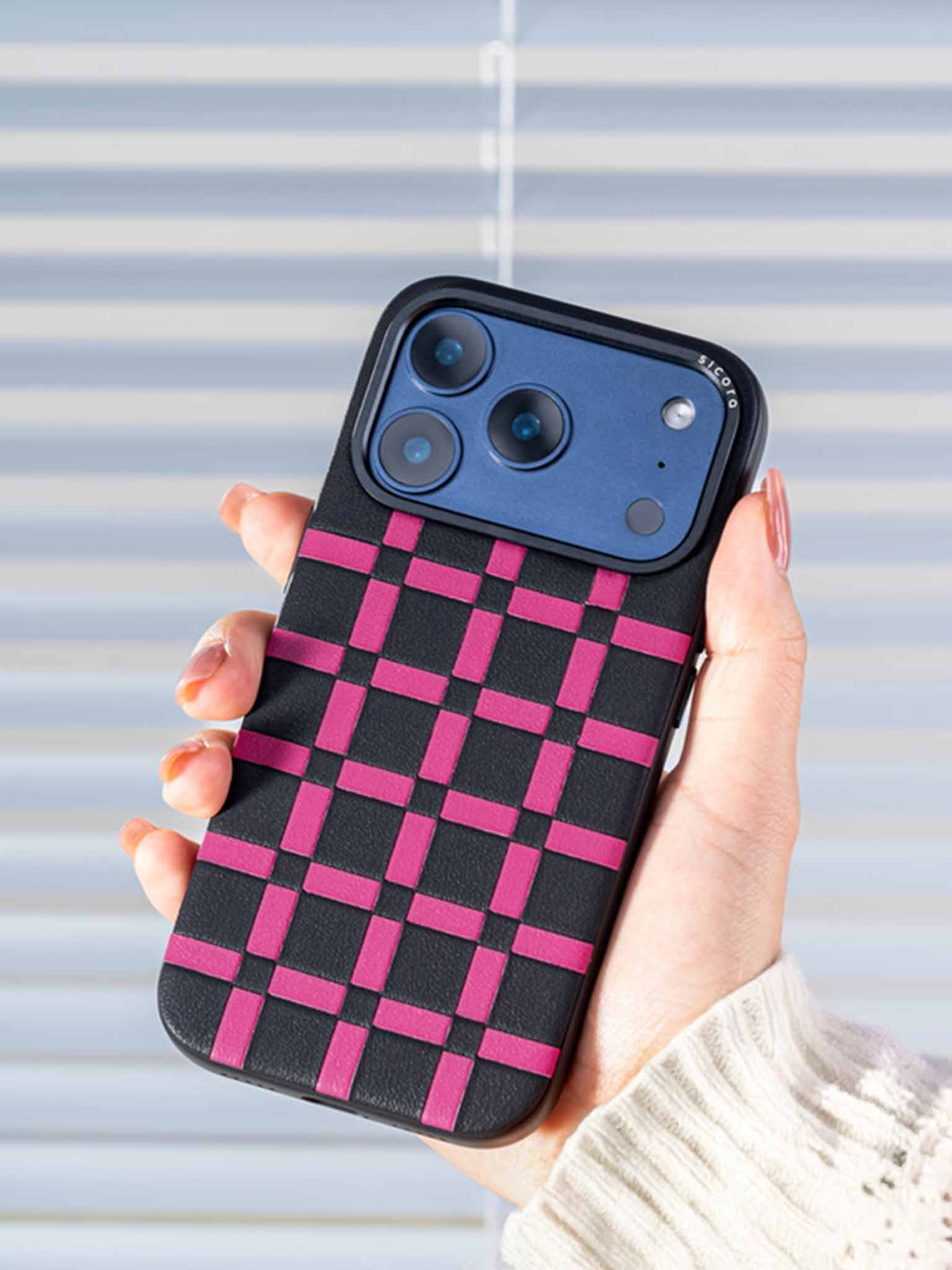 Sicora gridplay phone case with black and magenta checkered pattern held by a woman against a light background