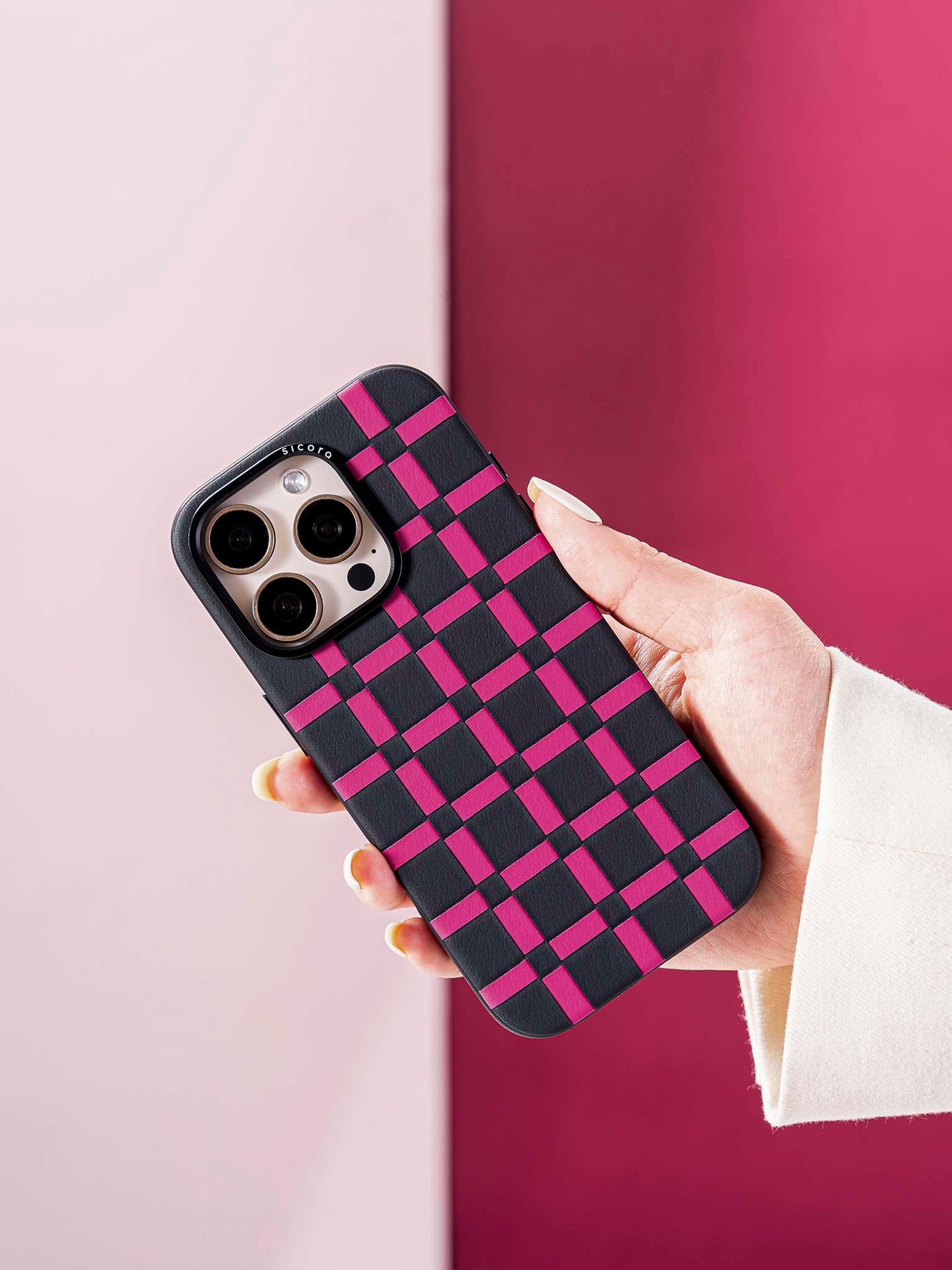 Hand holding a sicora black and pink handwoven gridplay iphone case