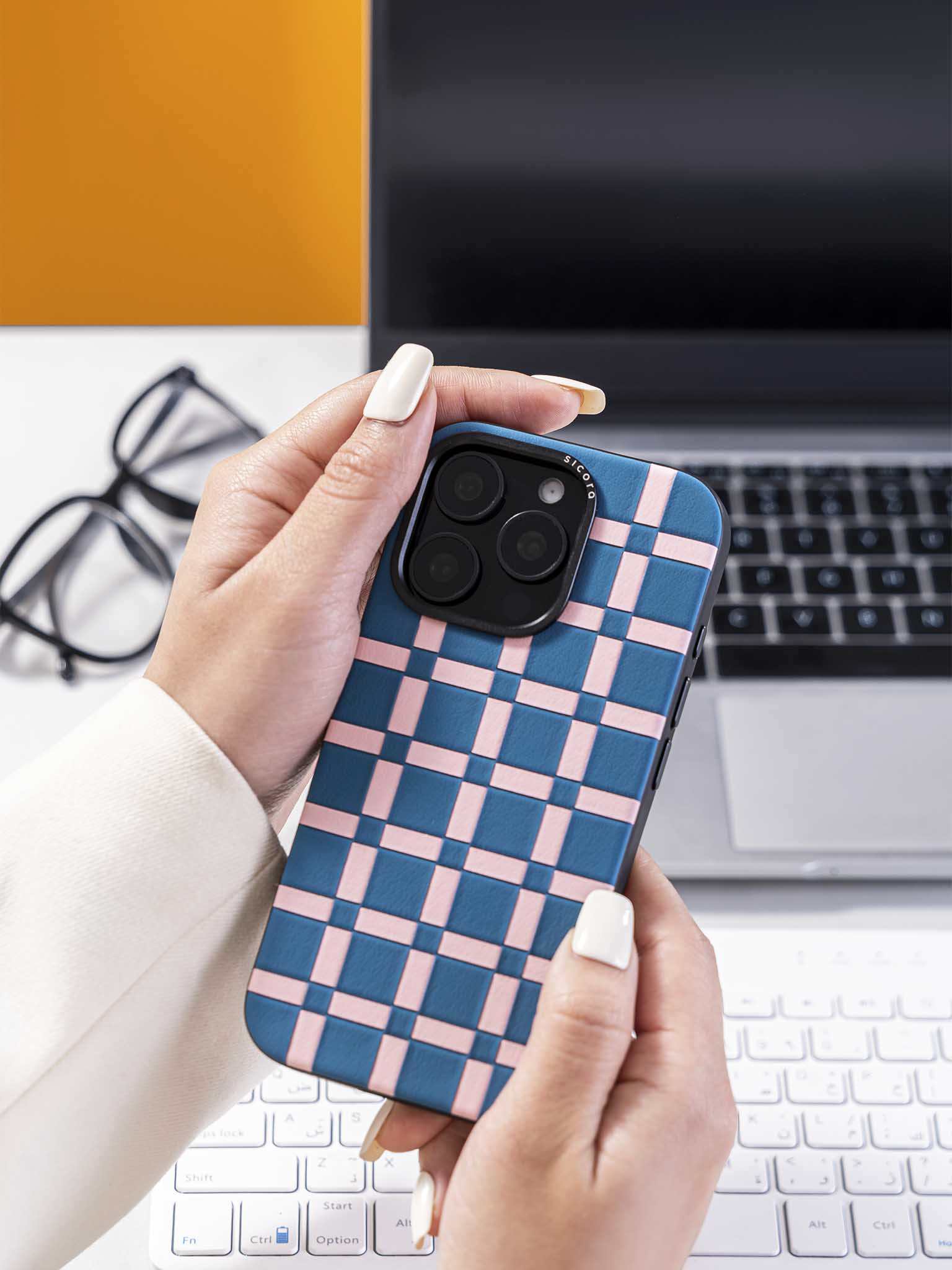 Hands holding a sicora blue and pink handwoven gridplay iphone case