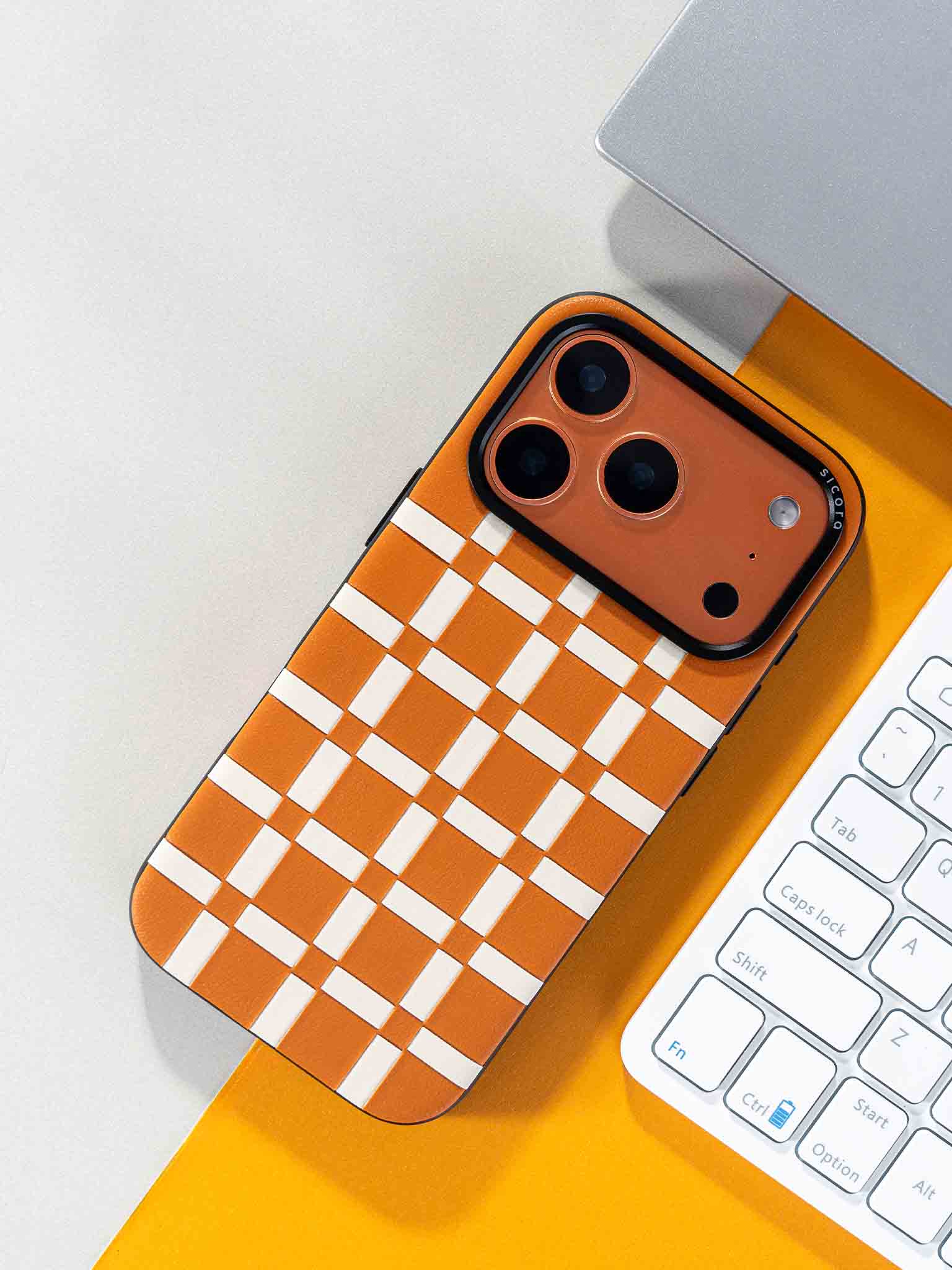 Sicora gridplay phone case with toffee gold and cream white checkered pattern on a desk