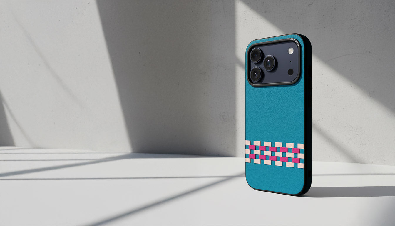 A sicora stitchon iphone case with silio silicone vegan leather in sea blue, pink and magenta geometric pattern on a cement textured background