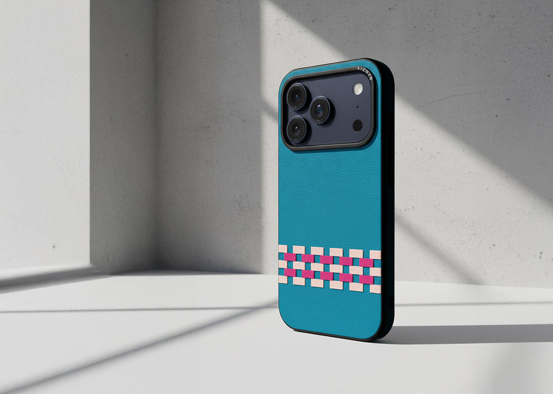 A sicora stitchon iphone case with silio silicone vegan leather in sea blue, pink and magenta geometric pattern on a cement textured background