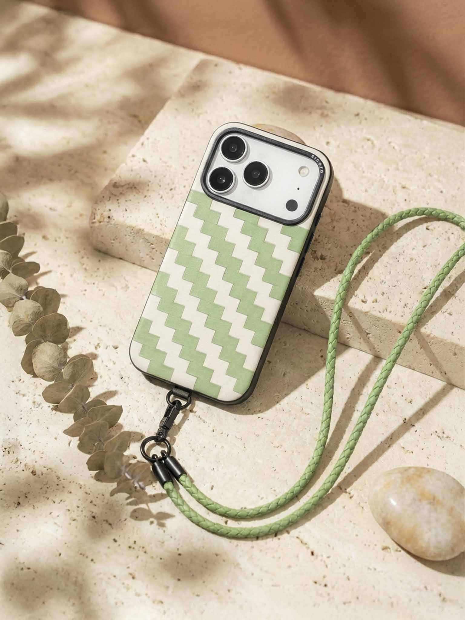 sicora zigzag phone case with green and white pattern and lanyard on a stone surface