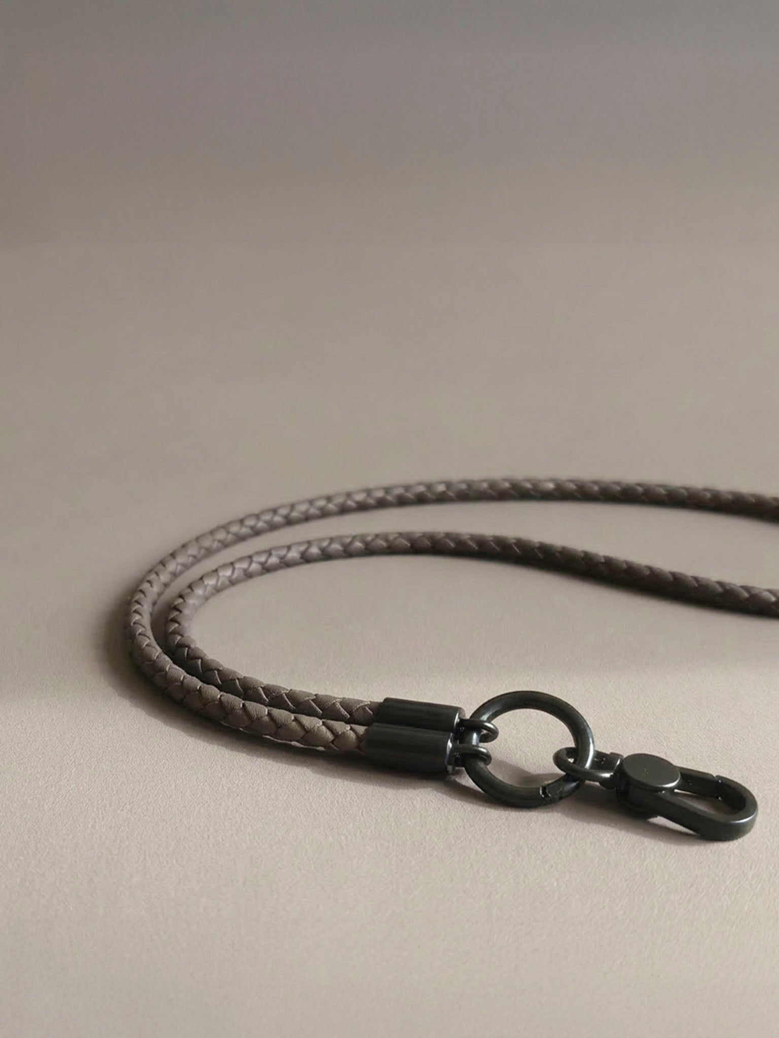 sicora gray braided cord with black metal clasp on a beige background