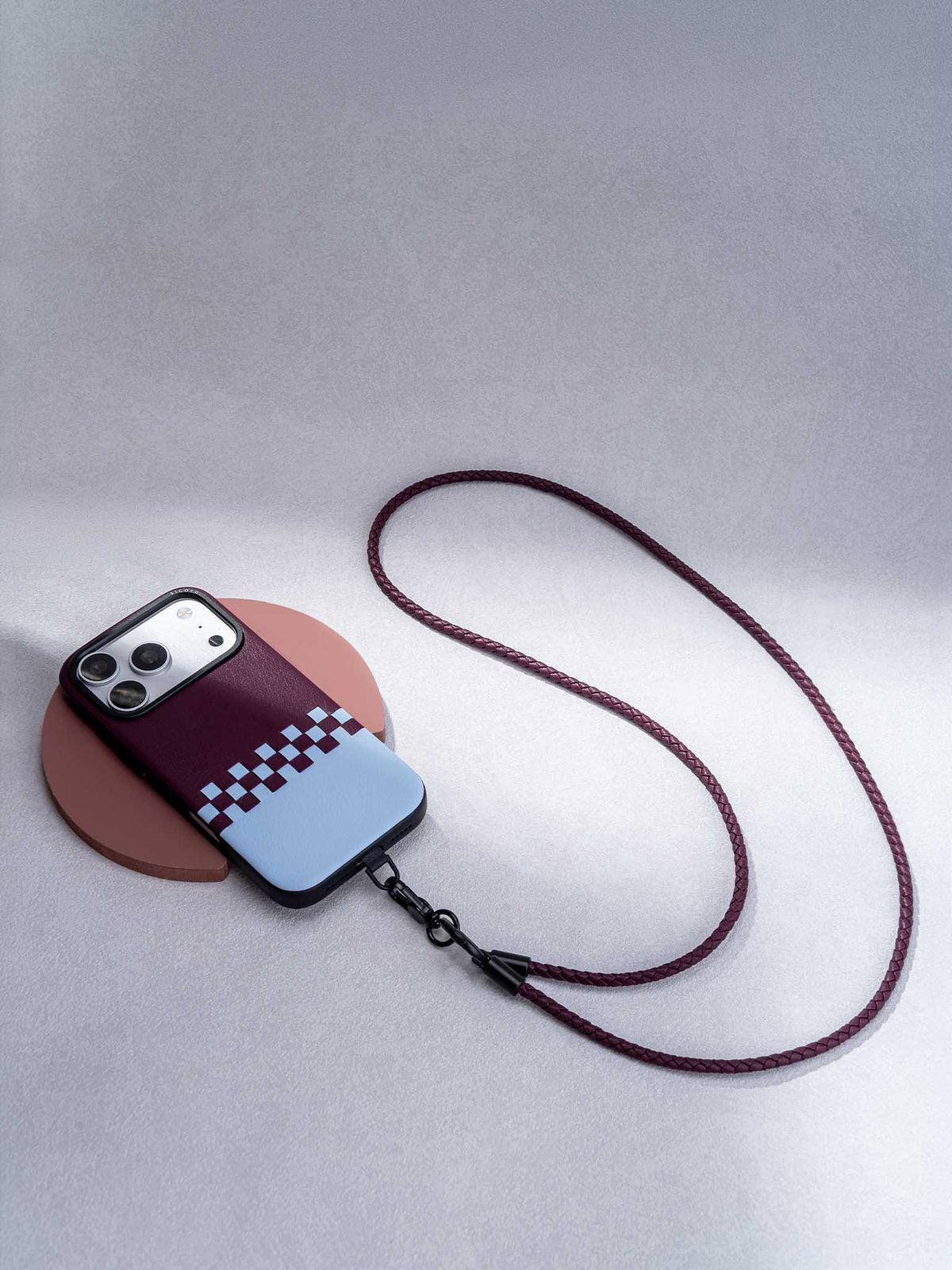 sicora iPhone 18 pro / iPhone 17 pro vegan leather phone case, crossover case featuring a cherry purple and sky blue hand-woven leather color blocking pattern, attached to matching purple loop phone lanyard.