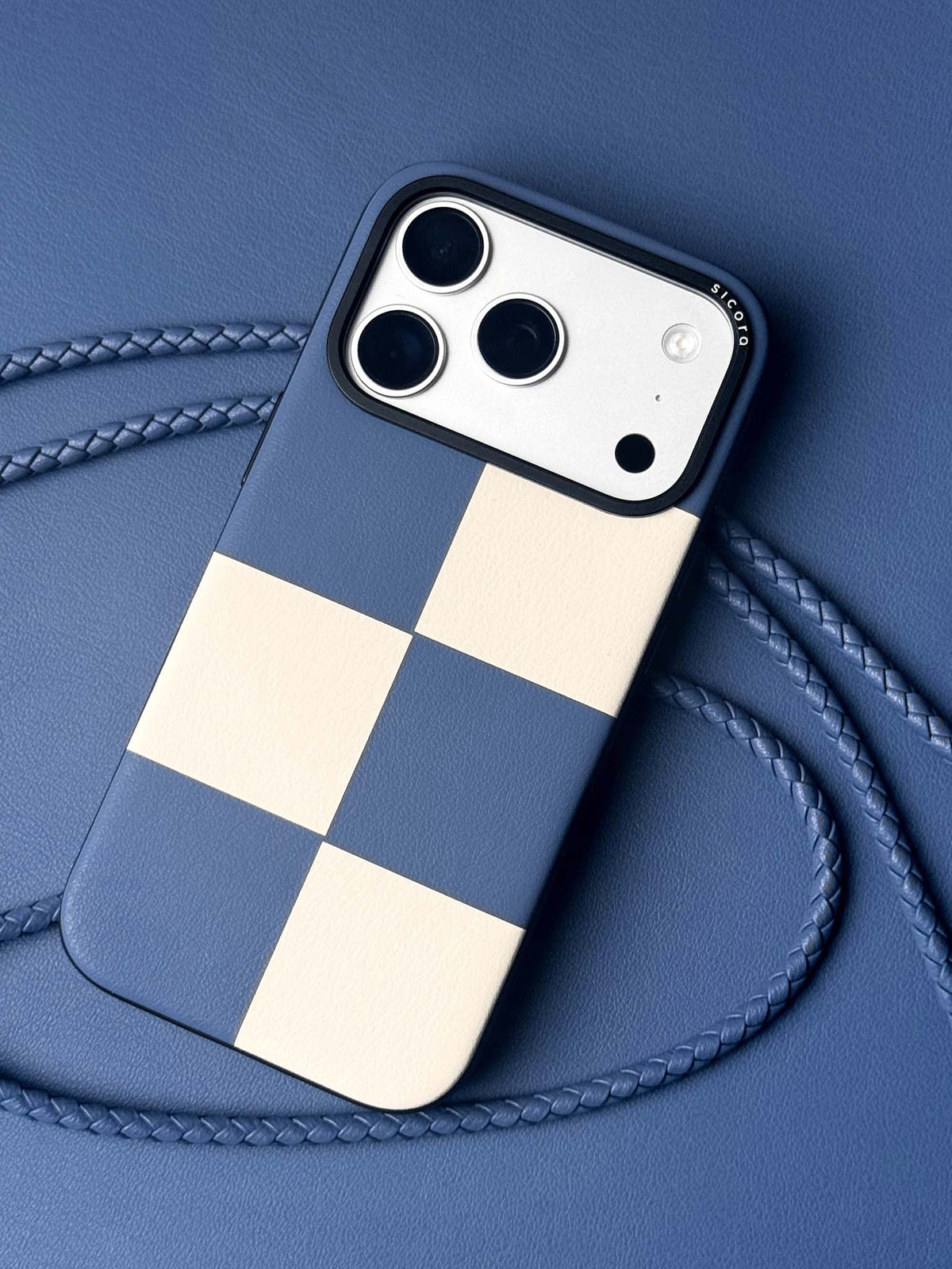 sicora iPhone 18 pro / iPhone 17 pro vegan leather phone case, macro case featuring a shadow blue and cream checkered leather marquetry pattern, braided phone lanyards and blue leather background