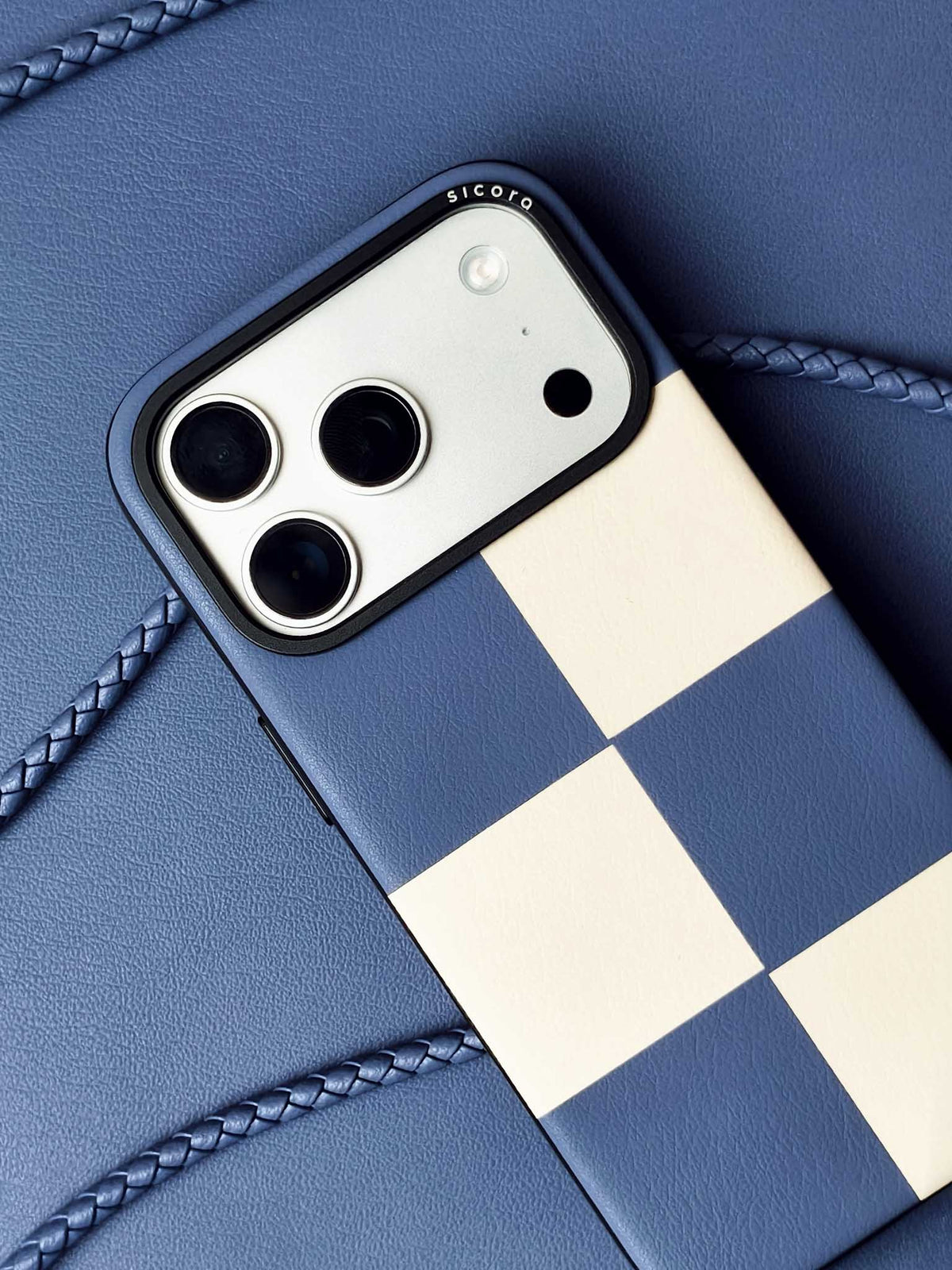 sicora iPhone 18 pro / iPhone 17 pro vegan leather phone case, macro case featuring a shadow blue and cream checkered leather marquetry pattern, braided phone lanyards and blue leather background
