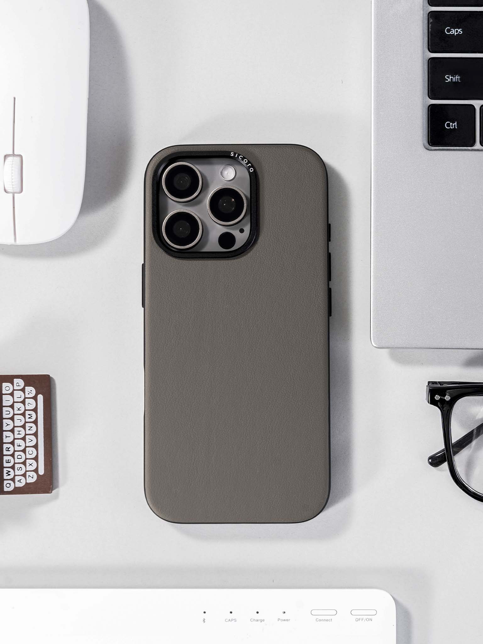 A gray sicora handmade vegan leather iPhone case on a desk