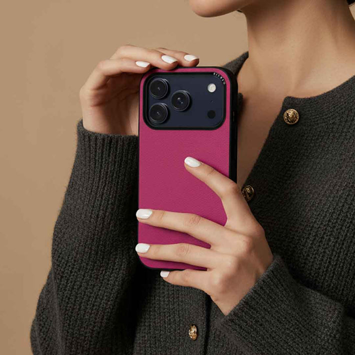 A woman holding a sicora moodblock iPhone case in magenta solid colored silio silicone vegan leather 