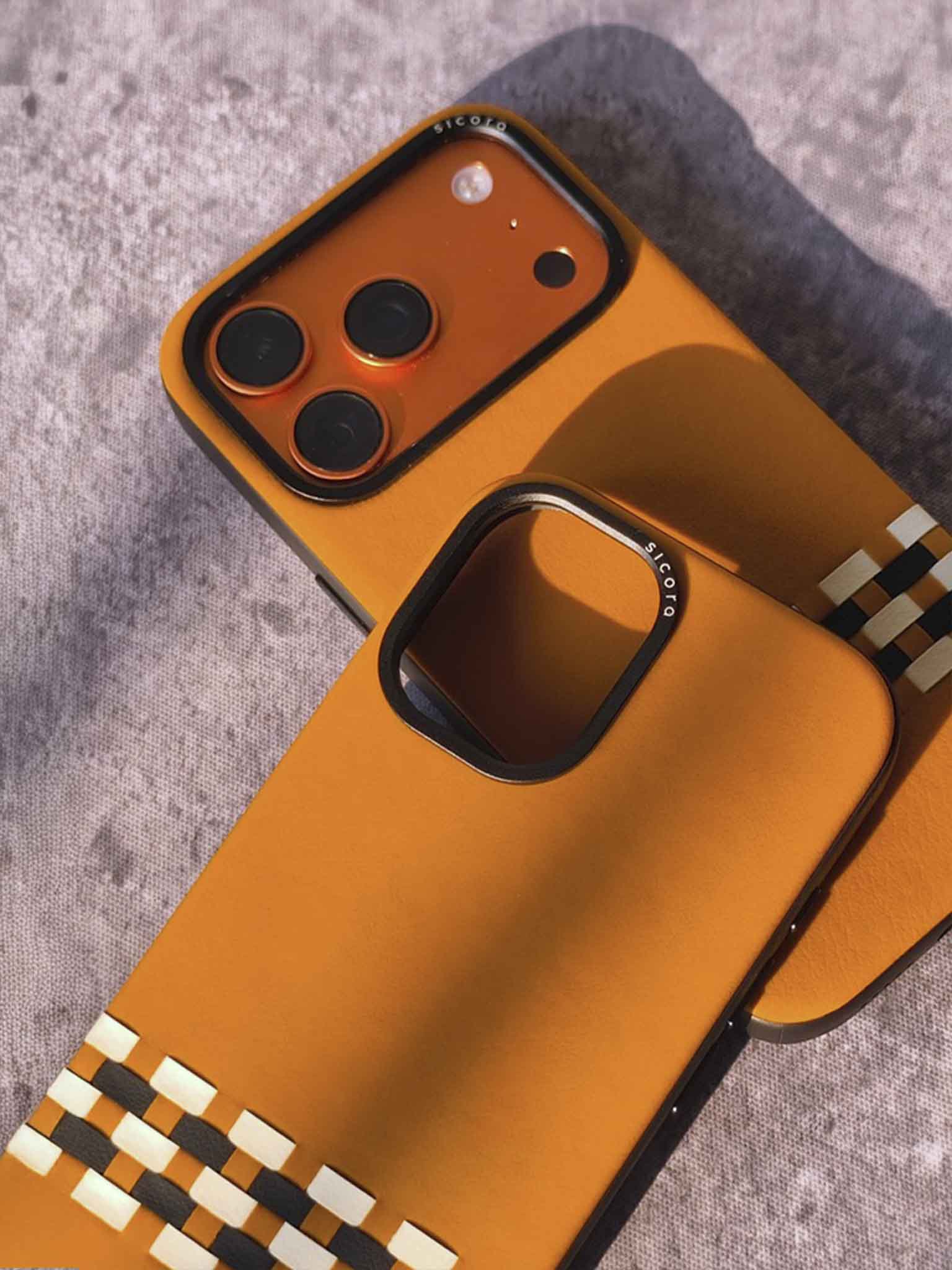 Close-up of toffee brown phone cases with woven stitchon pattern on a textured surface