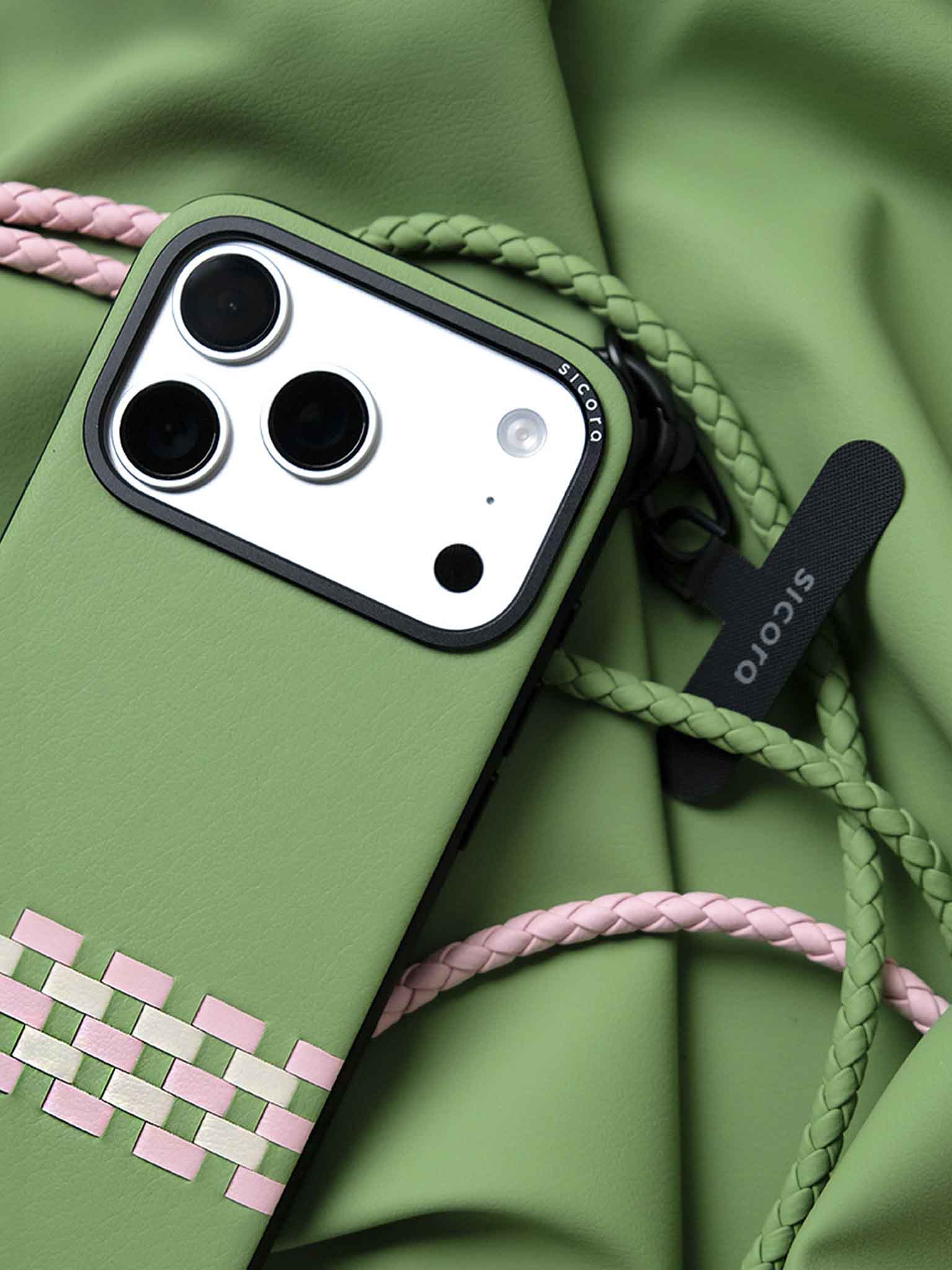 A green sicora stitchon iPhone 17 pro case with braided lanyards and black carabiner.