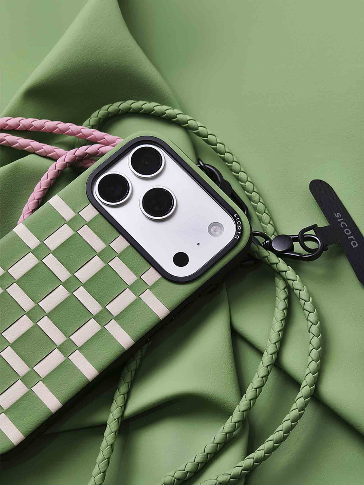 A green sicora gridplay iPhone 17 pro case with braided lanyards and black carabiner.