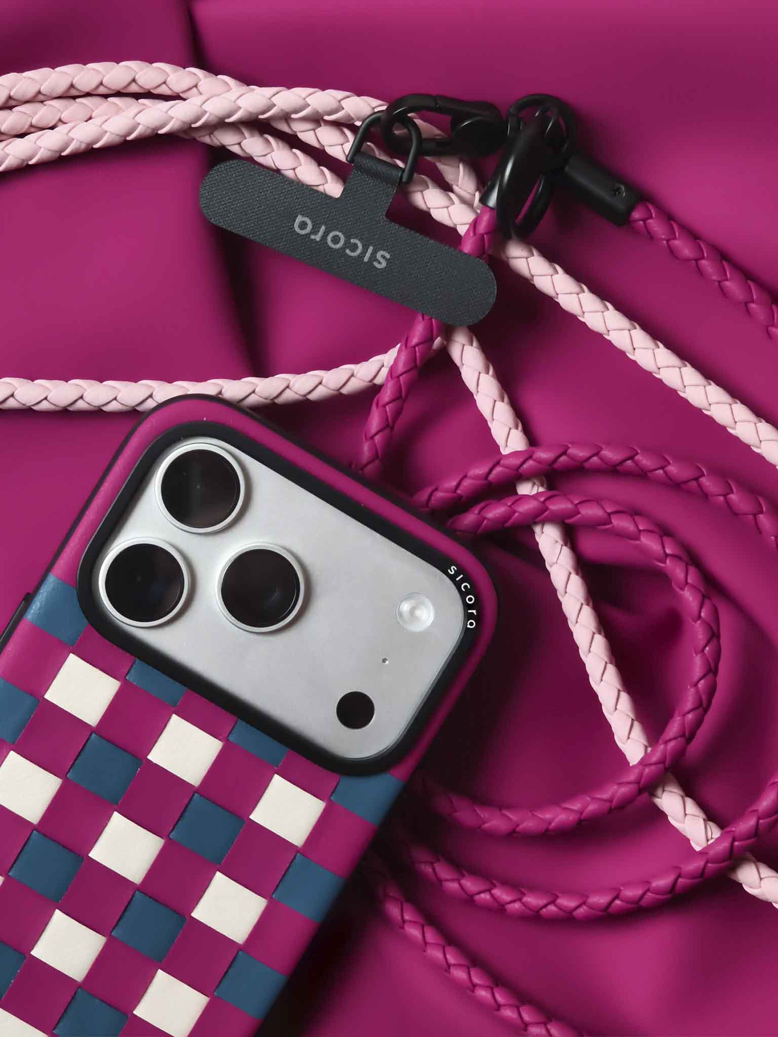 A magenta sicora checkerboard iPhone 17 pro case with braided lanyards and black carabiner.