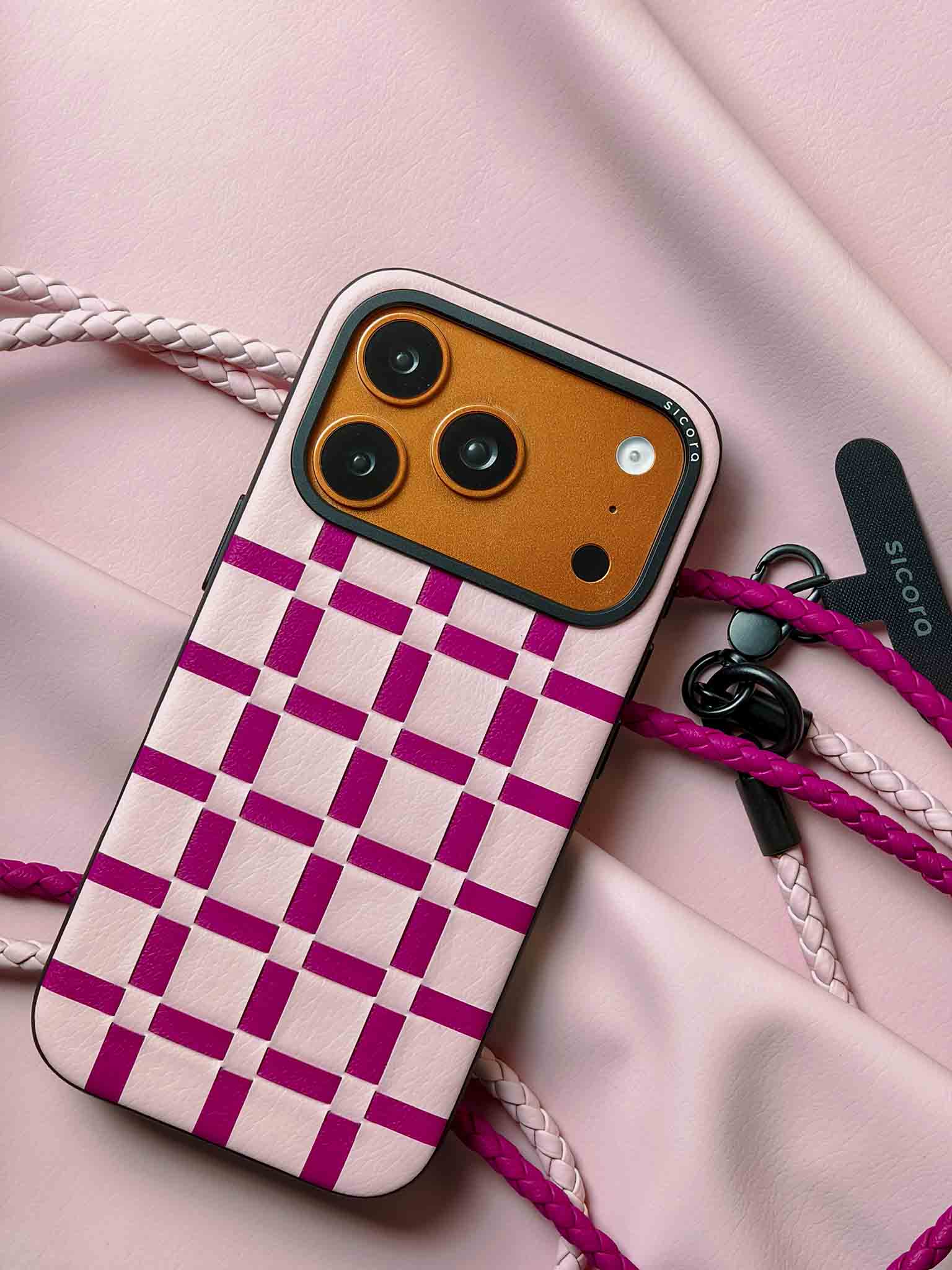 A pink sicora gridplay iPhone 17 pro case with braided lanyards and black carabiner.