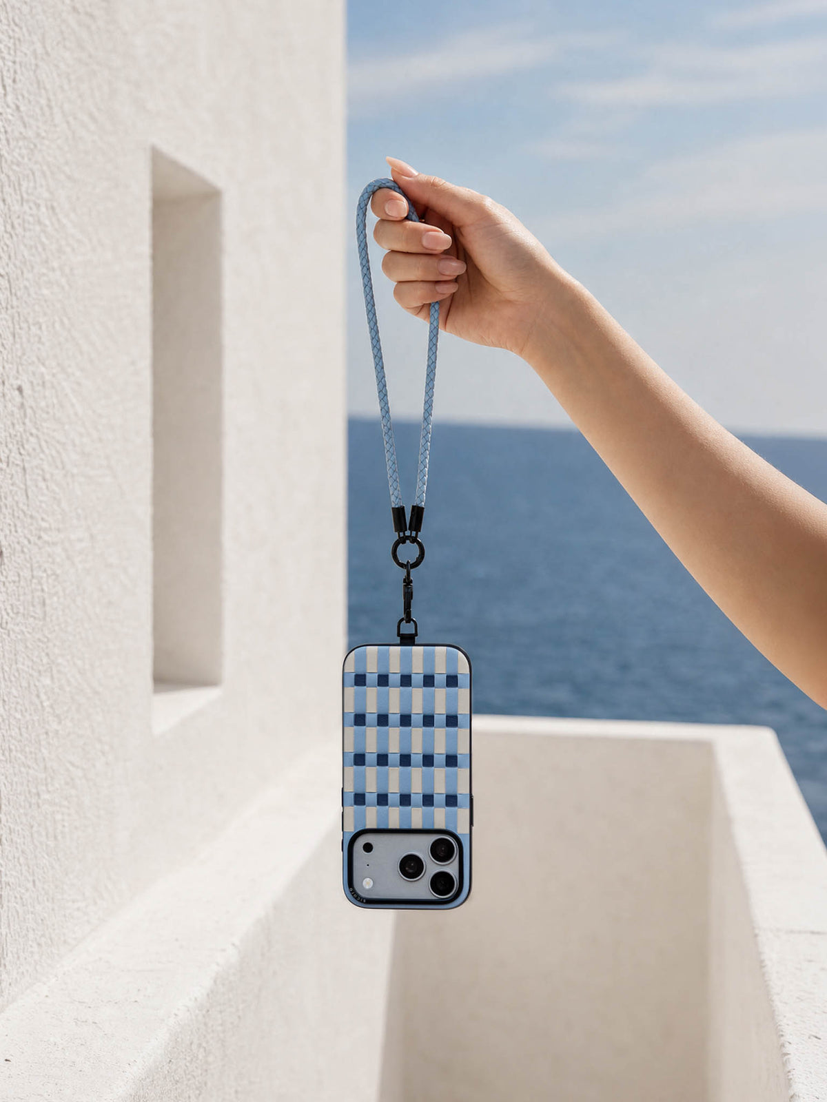 Hand holding a sicora light blue braided leather cord / short wristlet phone lanyard with a matching light blue pixel case iphone case.