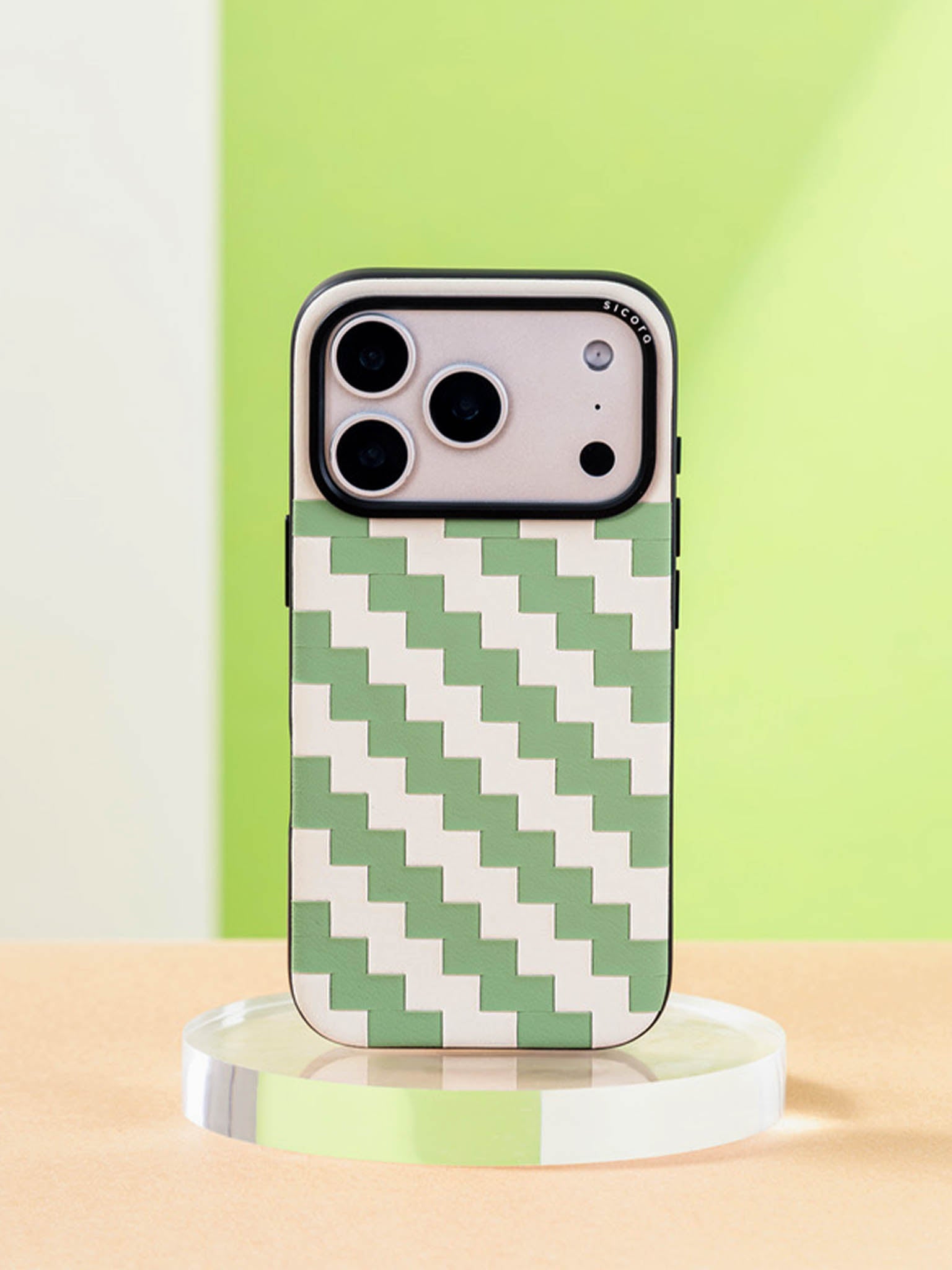 Sicora zigzag phone case with avocado green and cream white zigzag pattern on a clear stand against a green background