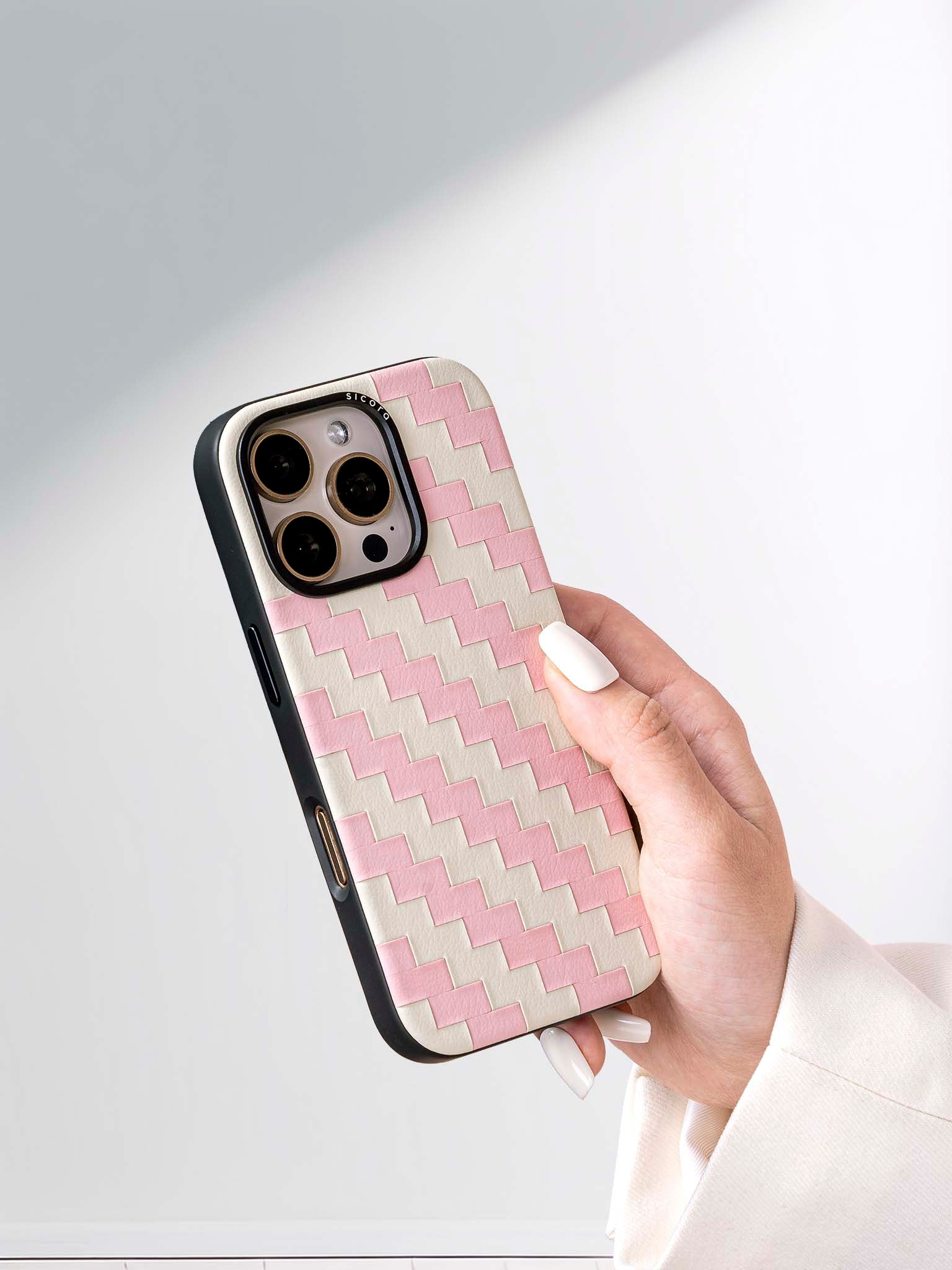 Hand holding a sicora pink and white zigzag iphone case 16 pro