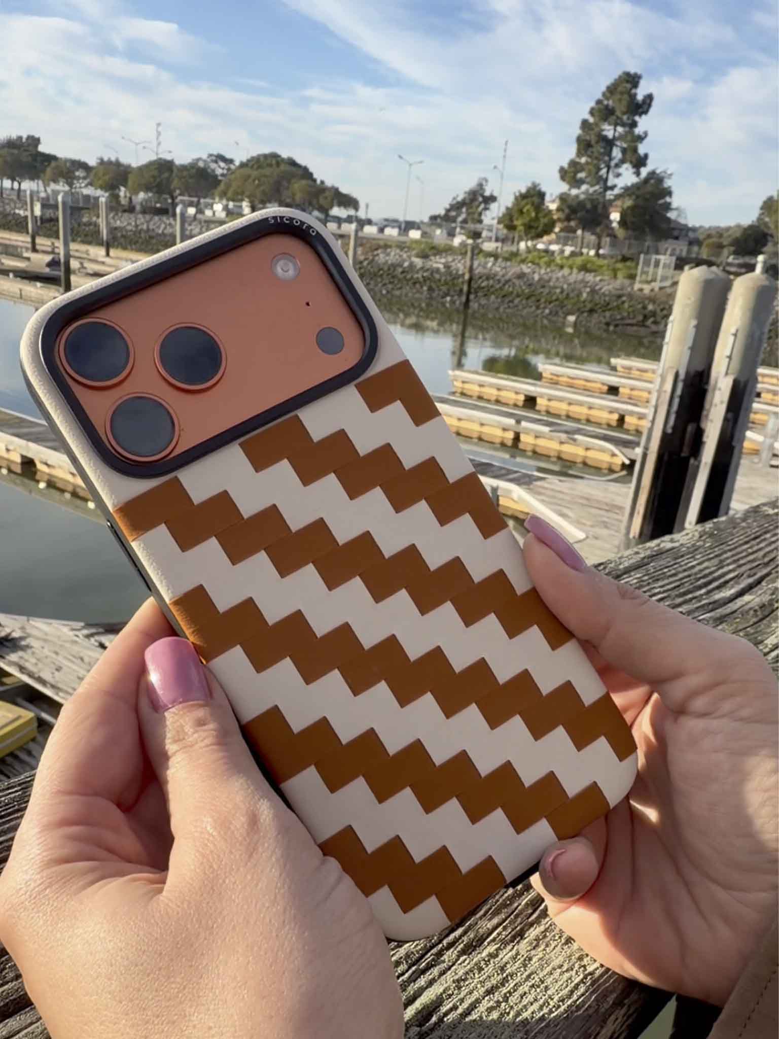 sicora toffee cream zigzag phone case held by a person outdoors.